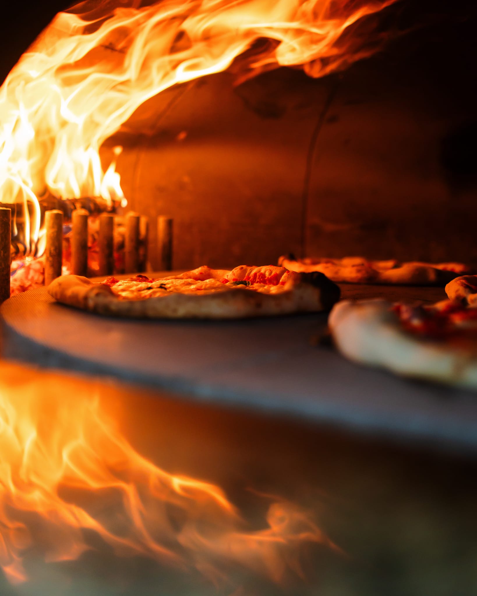 Pizza nel forno a legna con fiamme vive